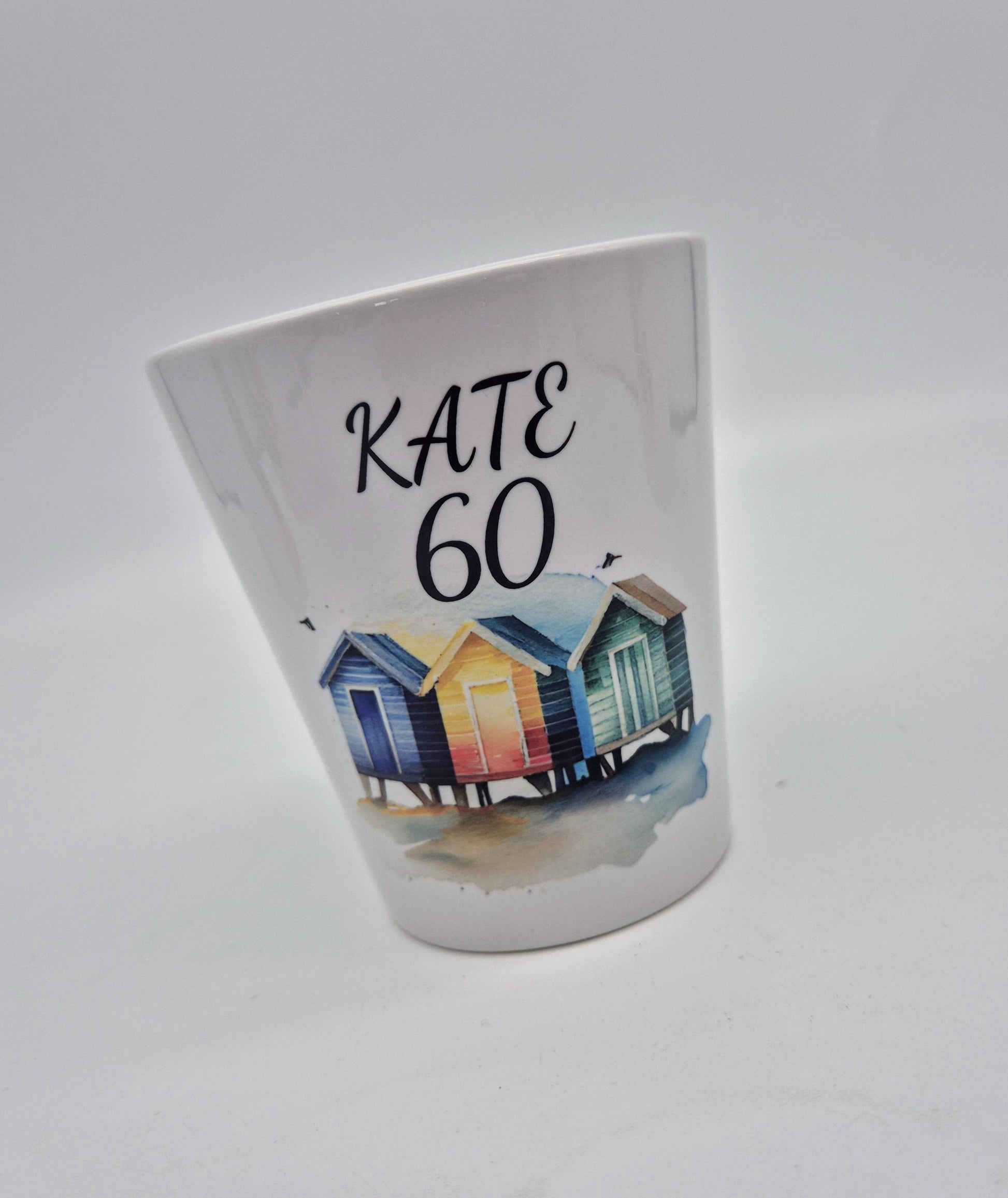 White plant pot with colourful beach huts design and 'KATE 60' text on a white background