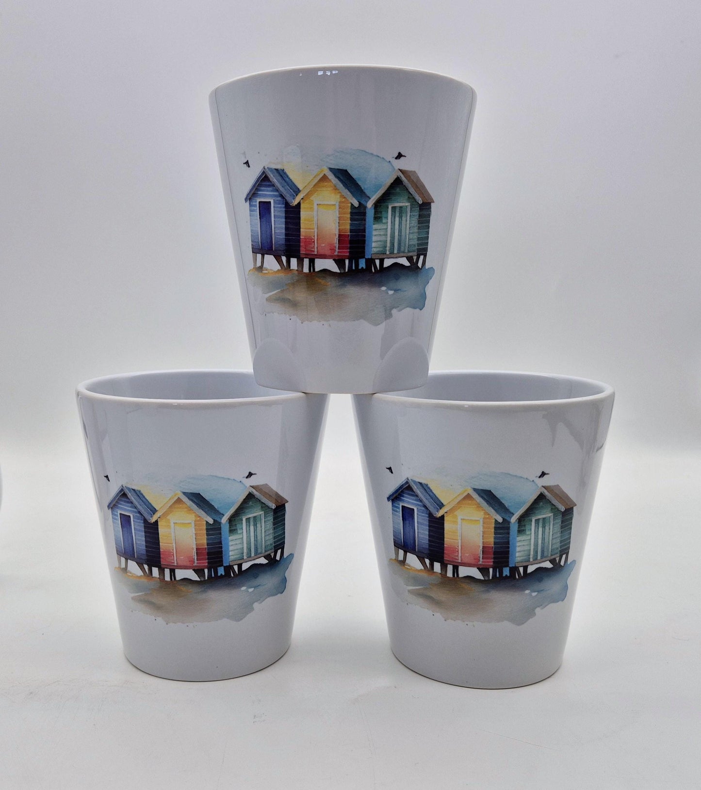 Three ceramic plant pot with beach hut design on a white background